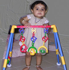 Standing up, holding to her playgym